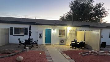 Un edificio residencial con un patio, mobiliario exterior y una puerta marcada con el número 105.