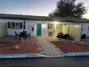 A residential building with a patio area, outdoor seating, and a door marked with the number 105.