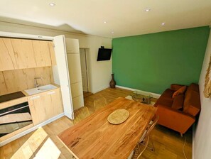 Un espacio habitable compacto con kitchenette, comedor y asientos.