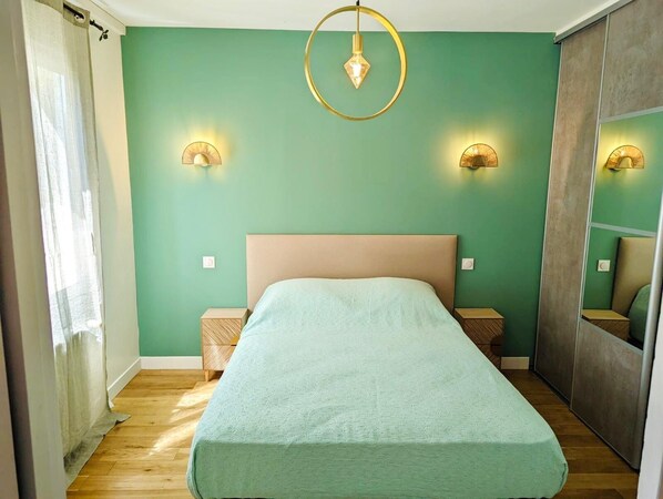 Un dormitorio con una cama, dos mesitas de noche, un espejo y una lámpara colgante.