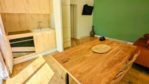 A compact kitchen with wooden cabinets, a built-in oven, and a dining area with a wooden table and chairs.