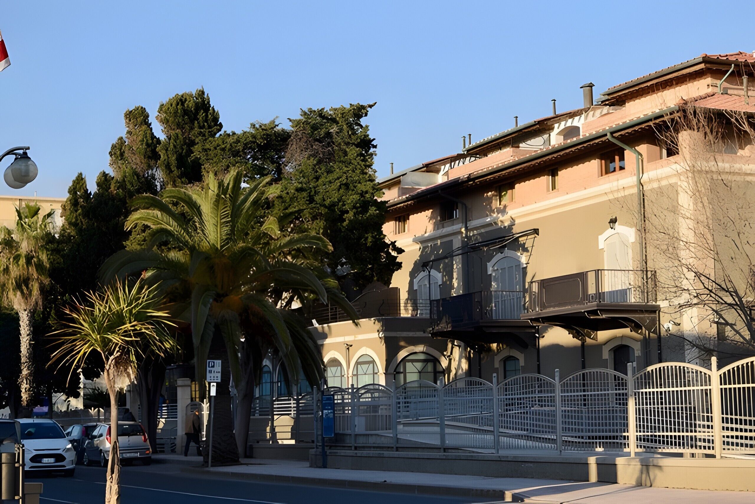 A building with arched windows, a balcony, and a gated entrance.
