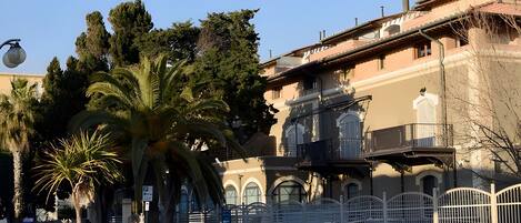 A building with arched windows, a balcony, and a gated entrance.