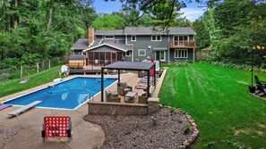 Un jardin à l’arrière d’une maison, avec une piscine, un espace salon extérieur et une terrasse couverte.