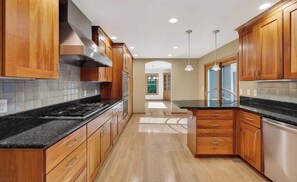 A modern kitchen with wooden cabinets, a black countertop, and a central island.