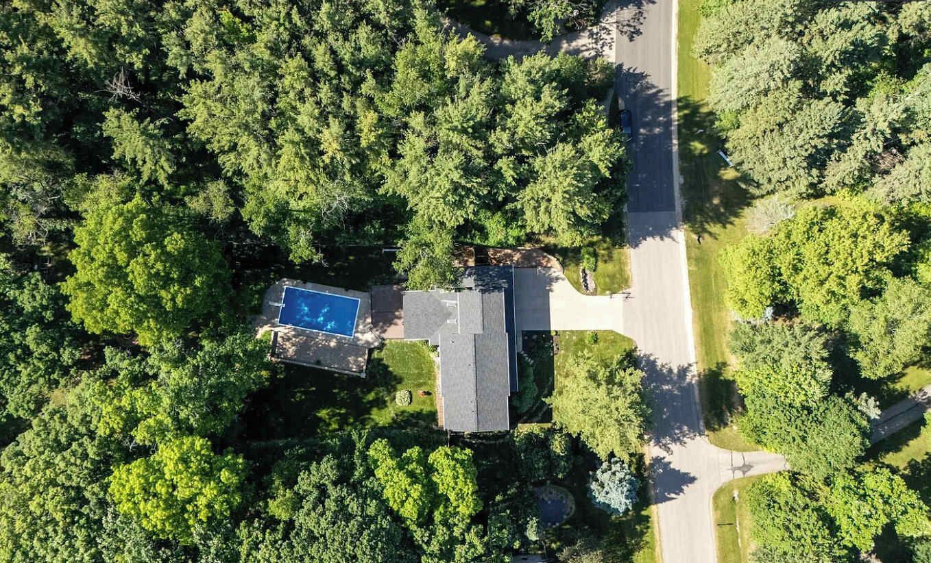 Vista aérea de una zona residencial con piscina, una casa y una carretera.