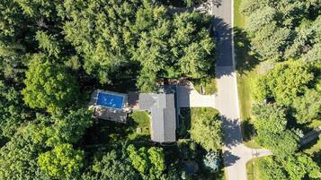 Vista aérea de una zona residencial con piscina, una casa y una carretera.