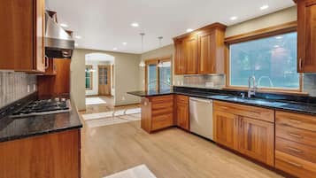 Una cocina moderna con armarios de madera, encimera negra y un ventanal grande.