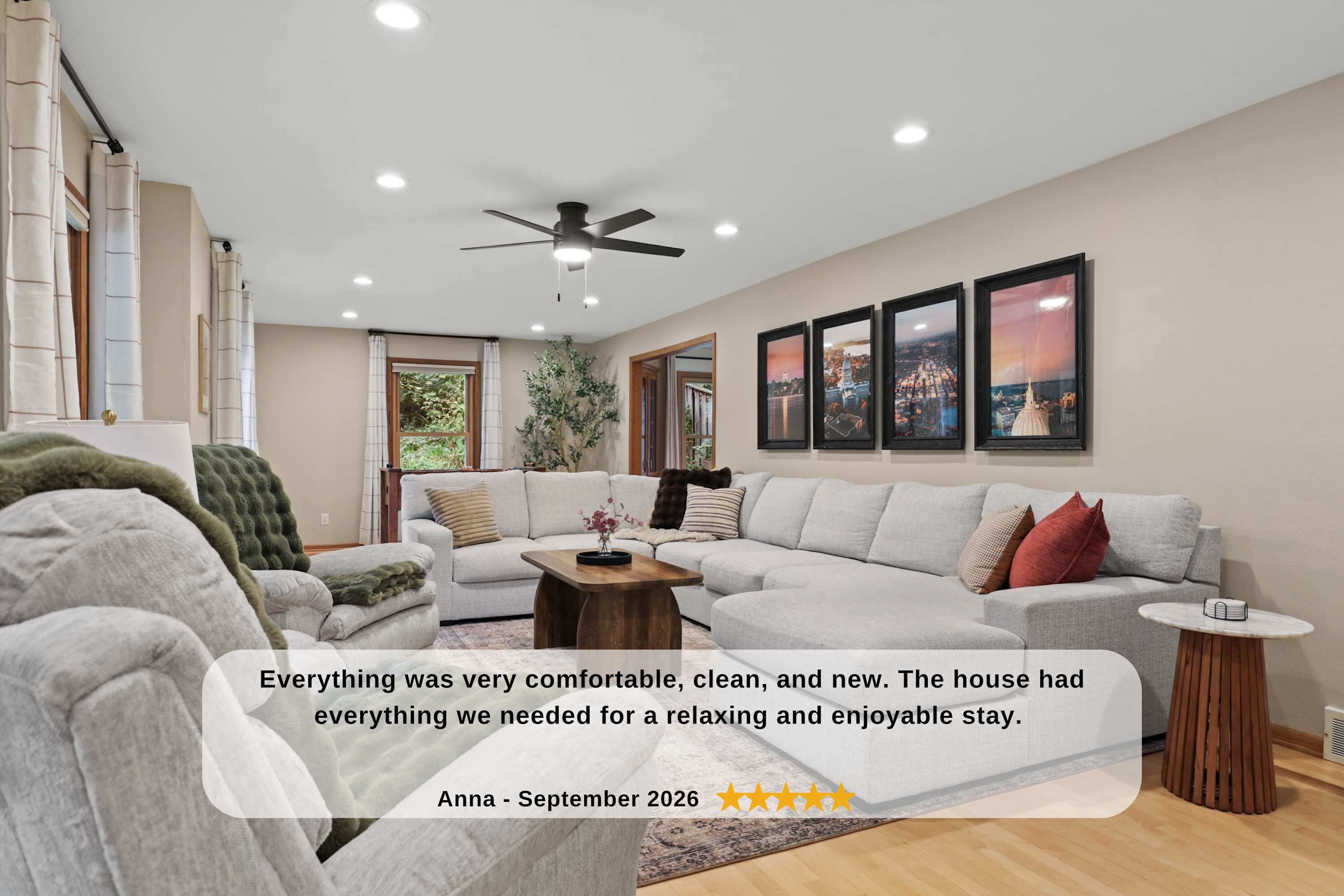 Large family room on the main level with sectional couch, two rocker recliner chairs, 65" smart TV, foosball table, and room darkening shades.