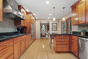 A modern kitchen with wooden cabinets, stainless steel appliances, and pendant lighting. - Heated Pool - Hot Tub - Sauna - Game Room - Pets (Sun Prairie)