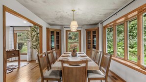 A dining room with a long table, wooden chairs, and a chandelier.