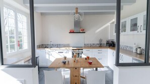 Eine moderne Küche mit weißen Schränken, einem Holztisch und zwei weißen Stühlen.