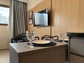 A modern hotel room with a dining table, two chairs, a TV mounted on the wall, and a window with curtains. - StayHome Vila Mariana Hausmitre - Gym  (São Paulo)