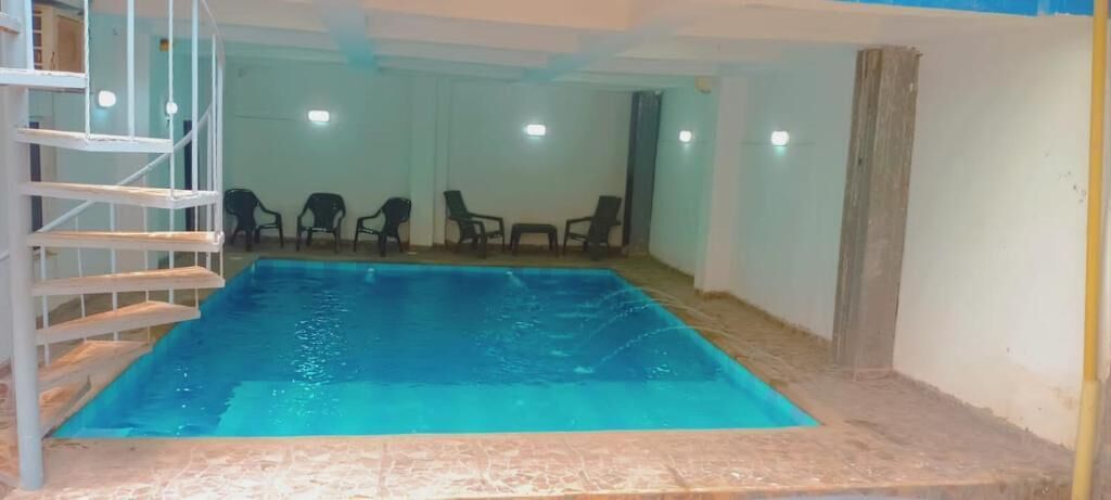 Une piscine intérieure dotée d’un plongeoir, entourée de chaises et d’un escalier.