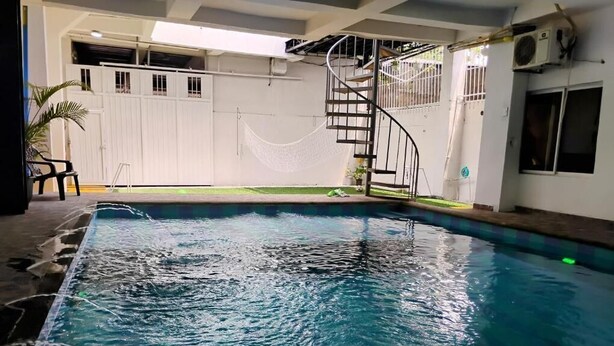 A swimming pool with a spiral staircase, a white fence, and a potted plant.