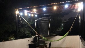 A patio with a table and chairs, a hammock, and string lights.