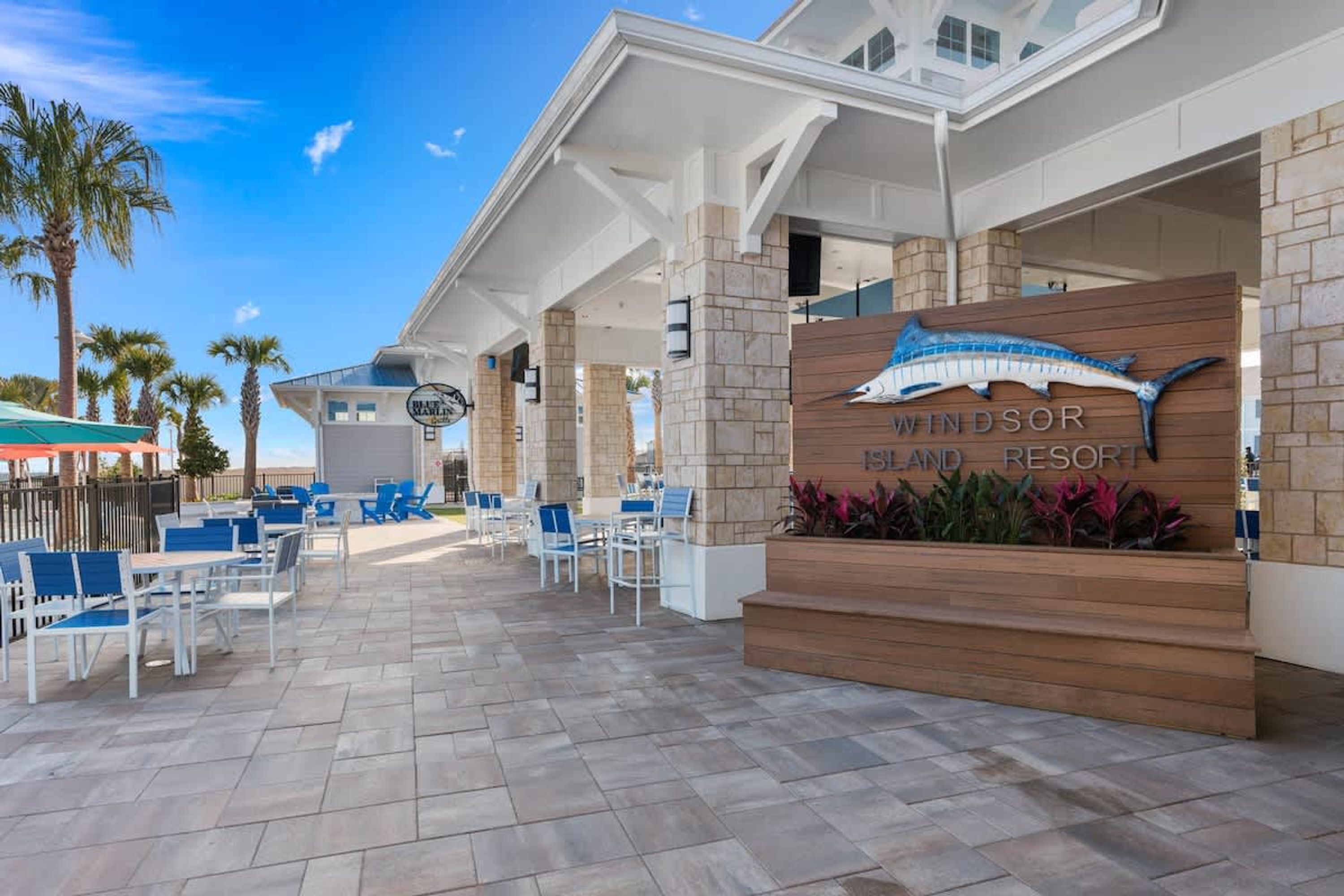 A resort with outdoor seating, a sign for 'Windsor Island Resort,' and palm trees in the background.