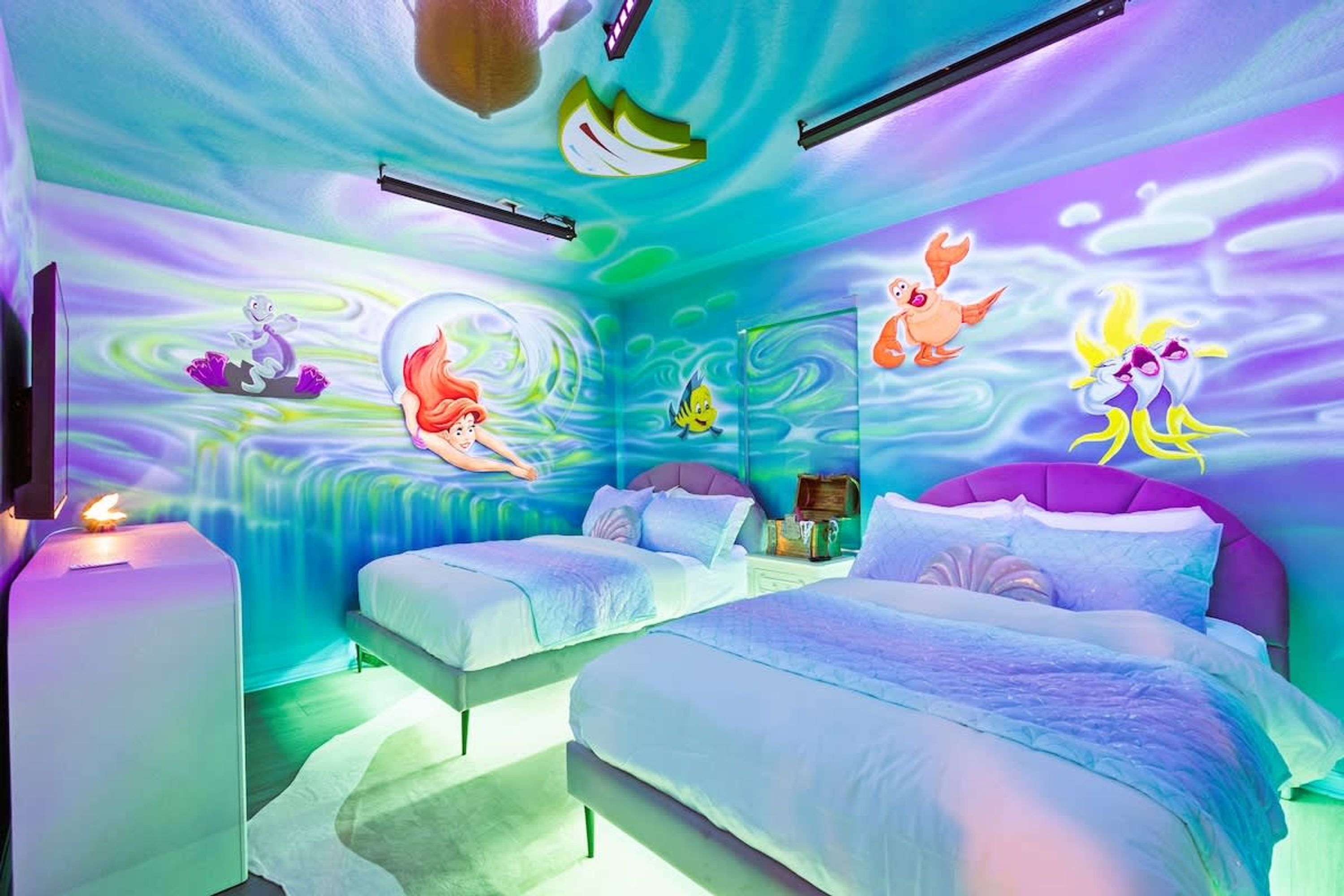 Ein Zimmer mit zwei Betten, einem Nachttisch und einem Wandbild.