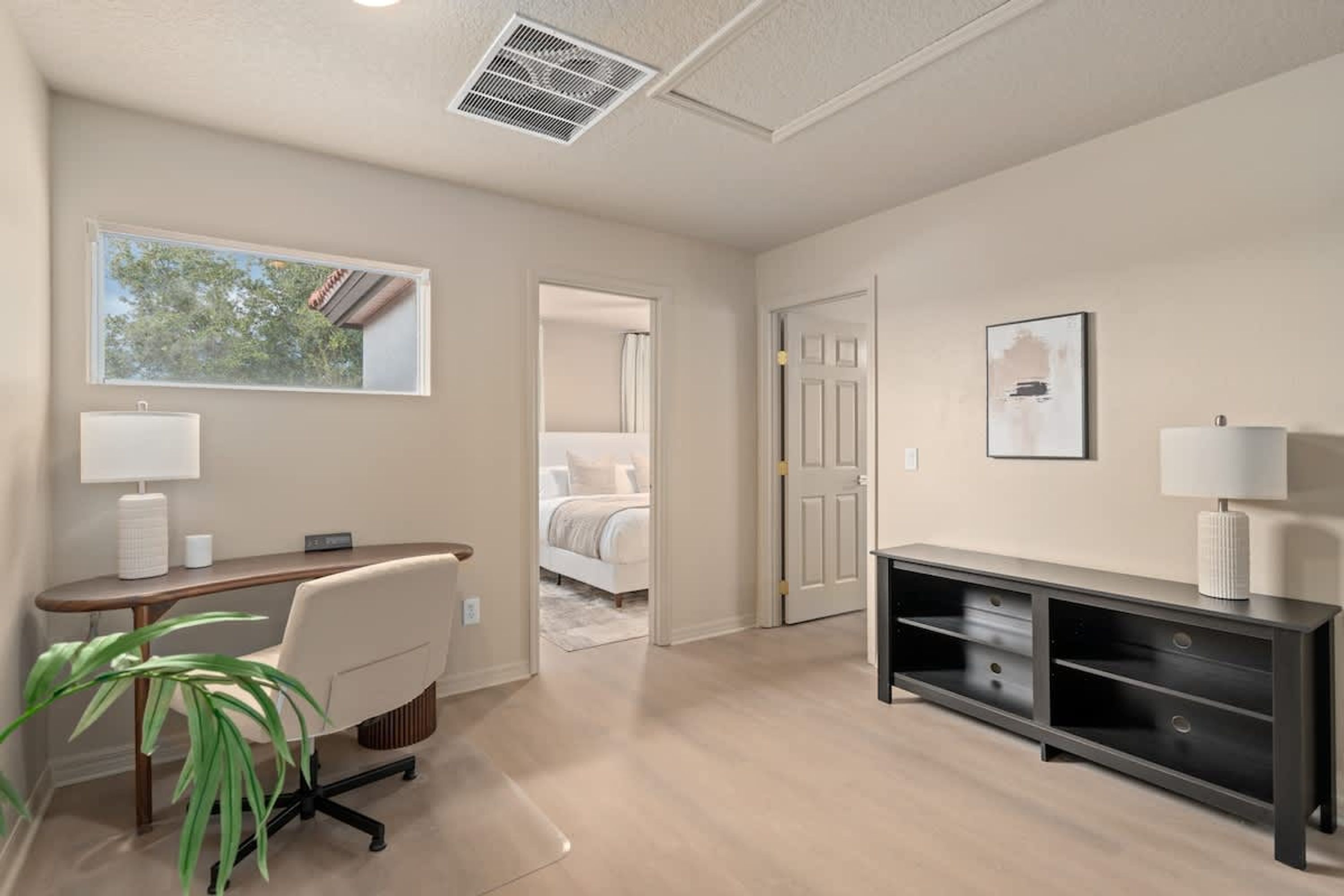 Une chambre d’hôtel moderne, équipée d’un bureau, d’une chaise et d’une grande fenêtre.