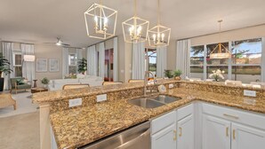 A modern kitchen with granite countertops, stainless steel appliances, and pendant lighting. - Disney Themed Resort Home With Lake View (Kissimmee)