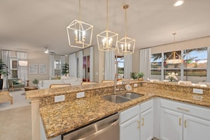 A modern kitchen with granite countertops, stainless steel appliances, and pendant lighting. - Disney Themed Resort Home With Lake View (Kissimmee)