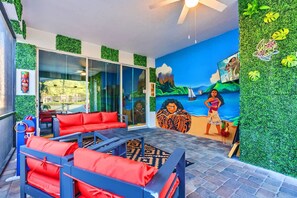 A room with a mural, red seating, and a view of the outdoors. - Resort Home With Pool Spa Game Room Near Disney (Kissimmee)