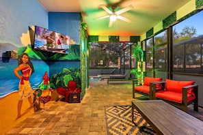 A room with a television, a ceiling fan, a pool, and outdoor seating. - Resort Home With Pool Spa Game Room Near Disney (Kissimmee)