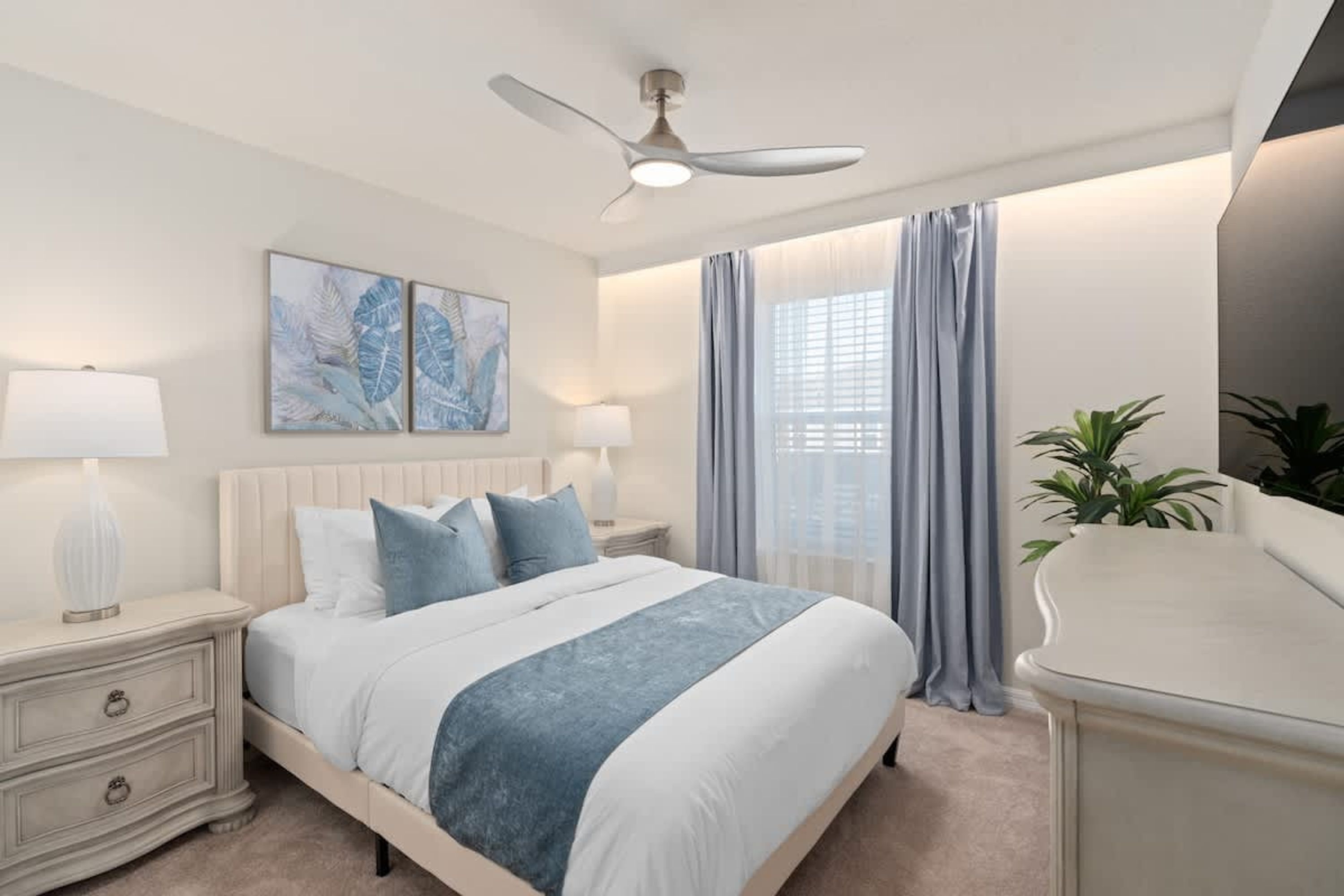 A bedroom with a bed, nightstands, a ceiling fan, artwork, curtains, and a plant.
