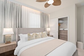 Ein Hotelzimmer mit einem großen Bett, zwei Nachttischen mit Lampen, einem Kleiderschrank und einem Deckenventilator.