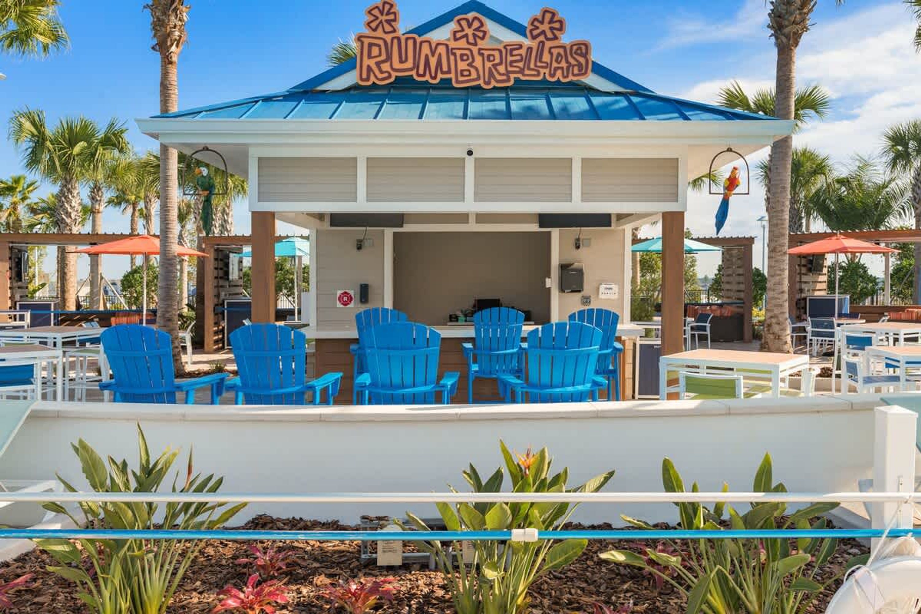 A beachside bar named 'RUMBRELLAS' with outdoor seating and palm trees.