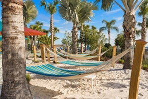 A beach area with hammocks, palm trees, and a sandy ground. - Windsor Resort Private Pool Theater Game Room (Davenport)