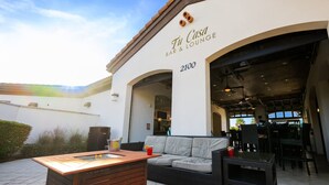 An outdoor seating area with a wooden table, a sofa, and a bar/lounge entrance. - Resort Home Private Pool and Spa Outdoor Theater (Kissimmee)