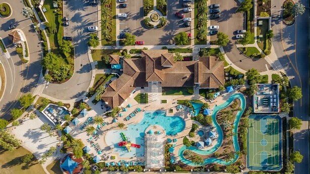 An aerial view of a resort with a swimming pool, a water slide, a basketball court, and a dock over water. - Resort Home Private Pool and Spa Outdoor Theater (Kissimmee)