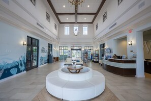 A spacious lobby with a central seating area, a reception desk, and a mural depicting underwater scenes. - Resort Home Private Pool and Spa Outdoor Theater (Kissimmee)