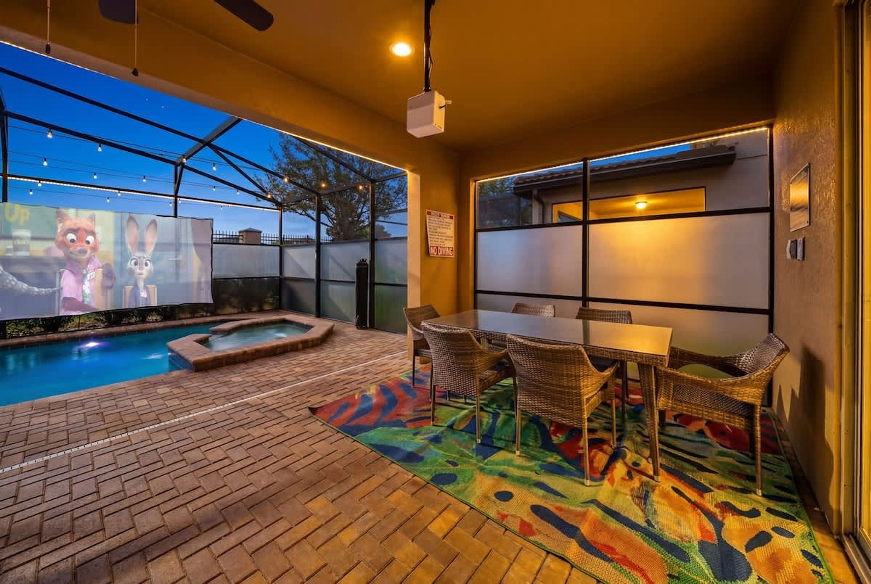 A pool area with a hot tub, wicker chairs, and a table.