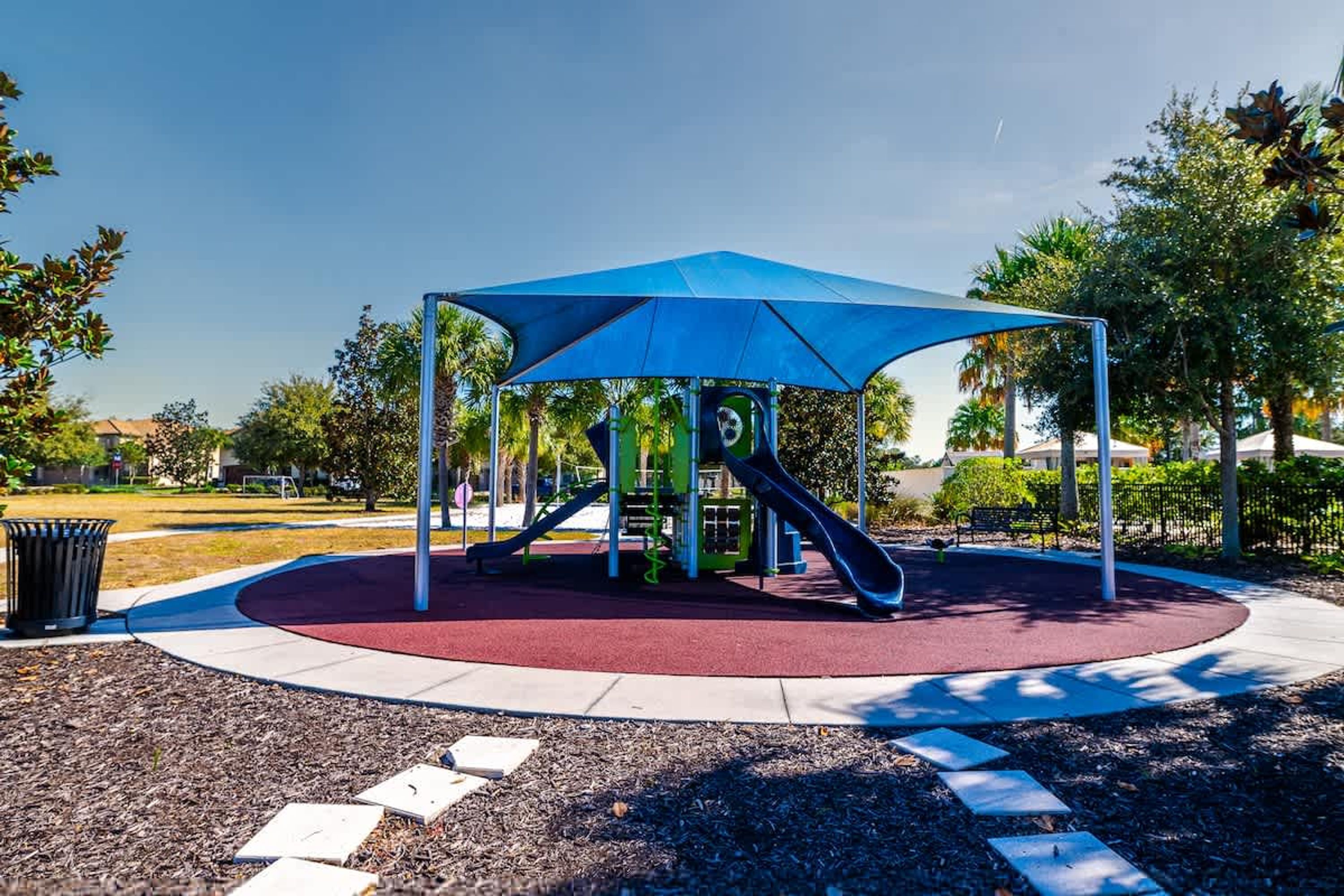 A playground with a blue canopy, a slide, and a climbing structure.