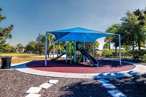 A playground with a blue canopy, a slide, and a climbing structure. - Resort Home Private Pool and Spa Outdoor Theater (Kissimmee)