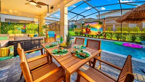 Un espace aménagé au bord de la piscine, avec une table en bois dressée pour les repas, des sièges d’extérieur et une vue sur la piscine.