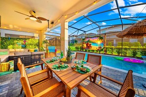 Ein Poolbereich mit Holztisch, gedecktem Esstisch, Sitzgelegenheit im Freien und Blick auf den Pool.