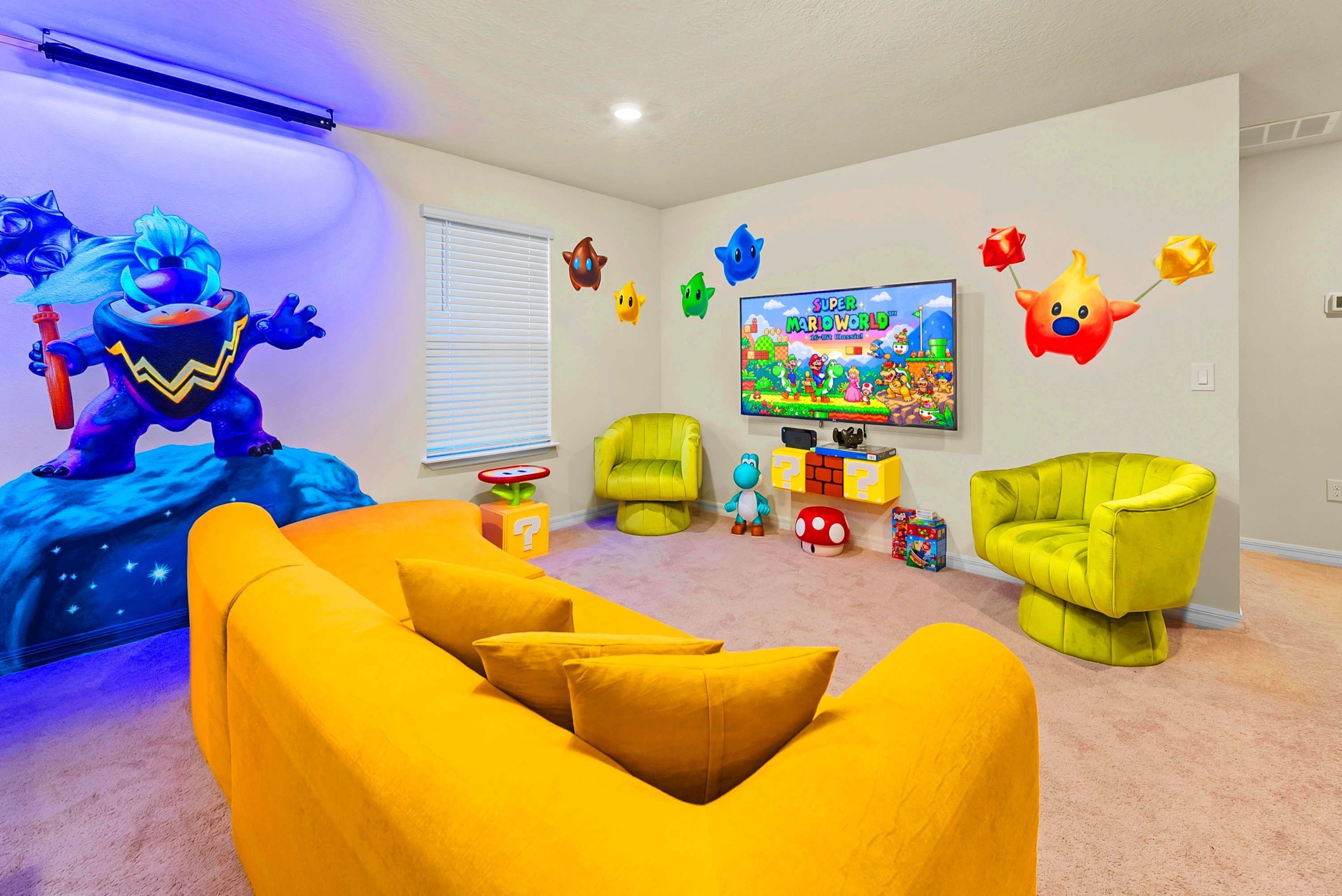 Una habitación con un sofá amarillo, sillas verdes, un televisor mostrando un partido y decoraciones de pared coloridas.