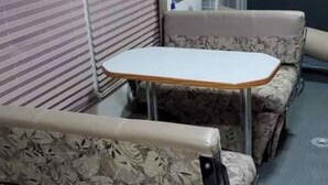 A compact RV interior with a small table and two cushioned seating areas. - Peaceful 1-bedroom recreational vehicle with AC in Spring Valley (Spring Valley)