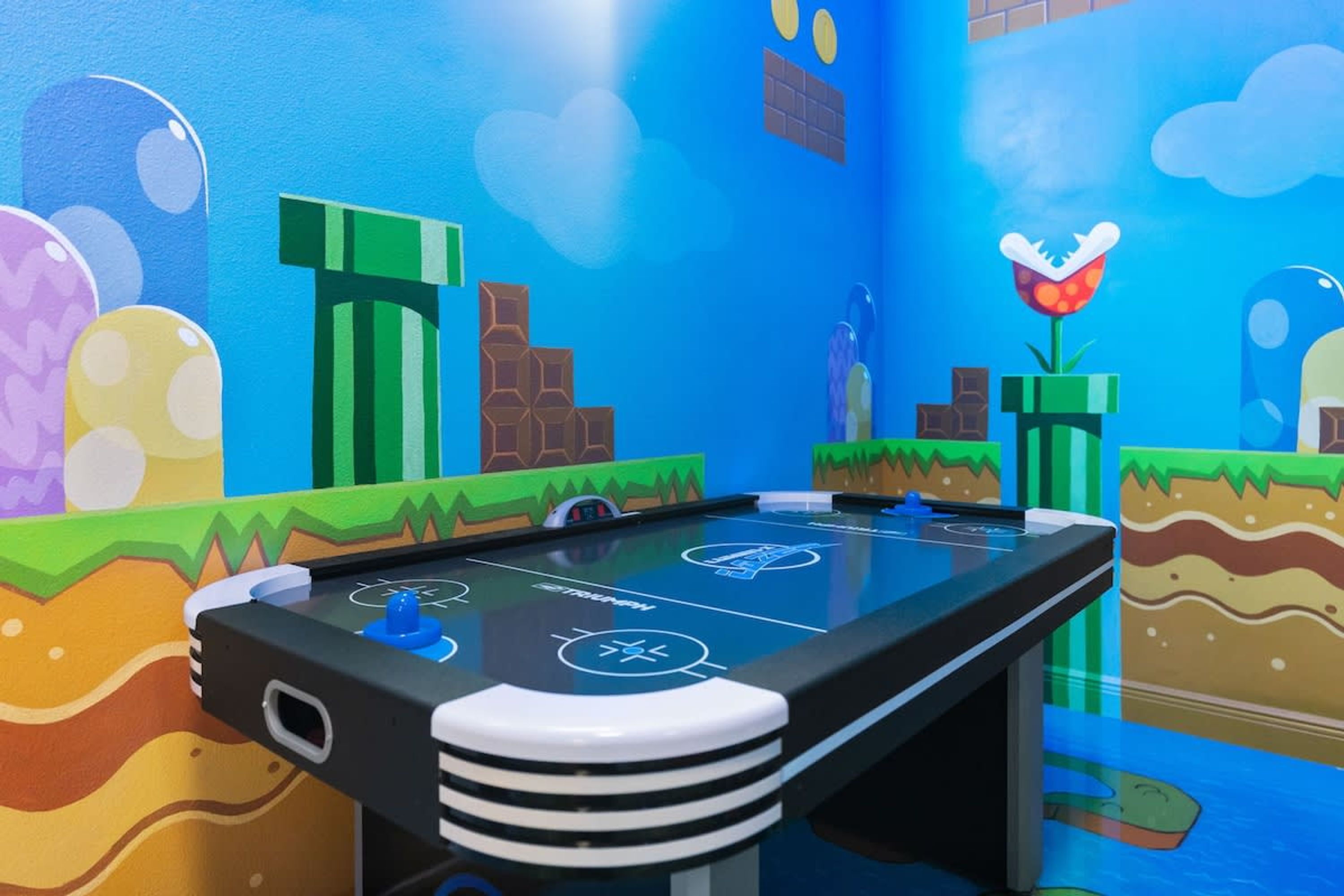 A pool table with a colorful, cartoon-themed mural on the walls.