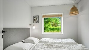 A bedroom with a bed, a bedside lamp, a window with a view of greenery, and a hanging light fixture. - "Adisl" - 300m to the fjord by Interhome (Højslev)
