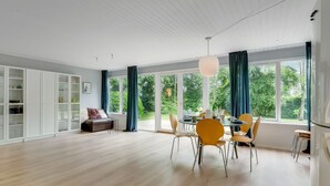 A spacious room with a dining area, a sofa, and a large window with curtains. - "Adisl" - 300m to the fjord by Interhome (Højslev)