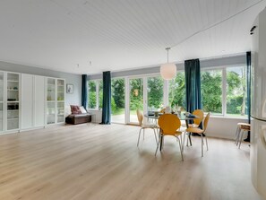 Ein geräumiges Zimmer mit Essbereich, einer Couch und einem großen Fenster mit Vorhängen.
