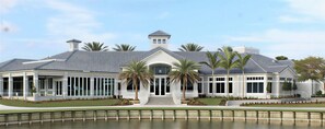 A large, single-story house with a wrap-around porch, a central entrance, and a small tower-like structure on the roof. - Completely Remodeled-Fully Furnished Modern 2BR/2BTH-Country Club Membership (Fort Myers)