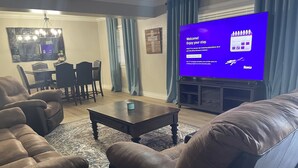 Een woonkamer met een bruine leren bank, een salontafel en een flatscreen-tv met het welkomstscherm van Roku.