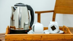 Una tetera de acero inoxidable MILEX y tazas blancas sobre una bandeja de madera.