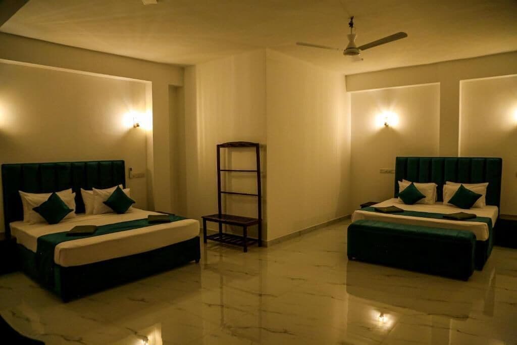 A hotel room with two beds, a ceiling fan, and wall-mounted lights.