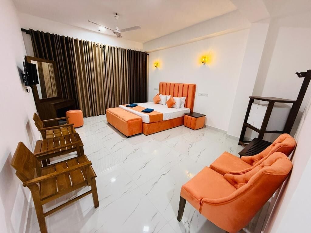 A modern hotel room with a bed, seating area, and a desk.